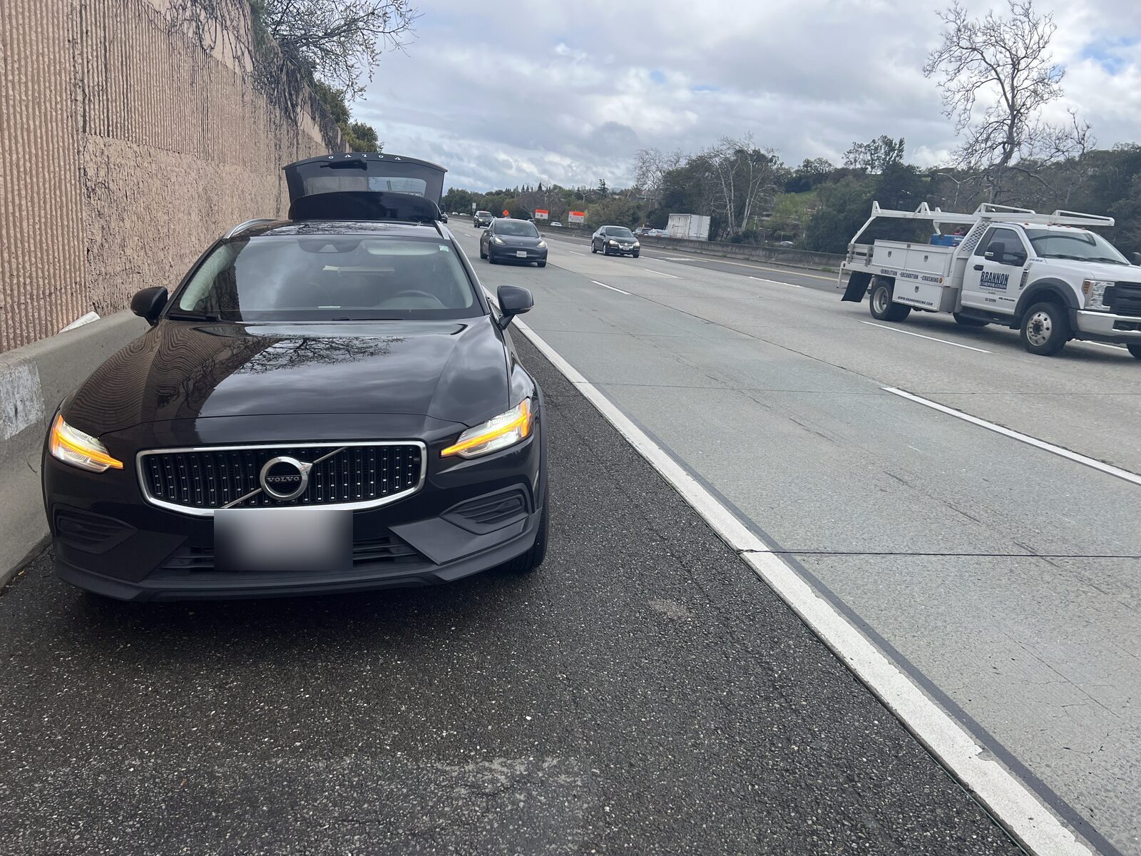 Car being serviced on a busy highway shoulder