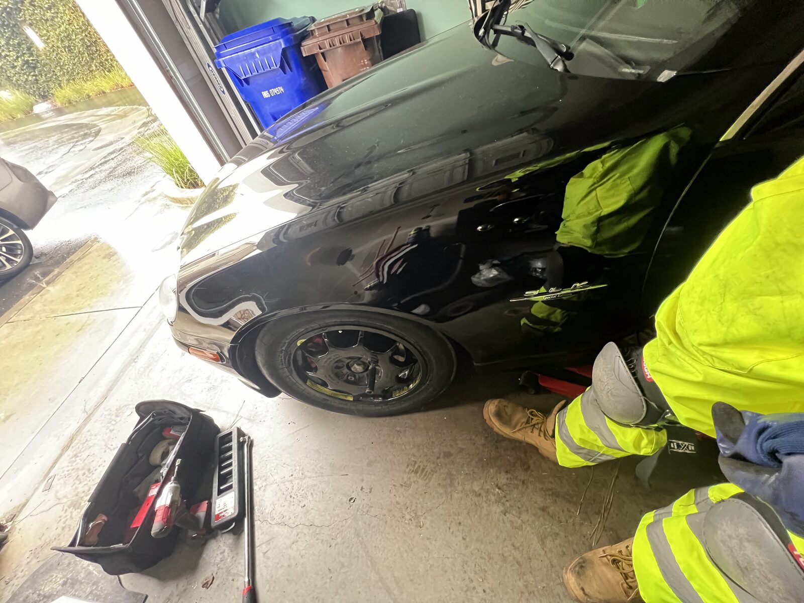 Technician working underneath a vehicle in hi-vis gear