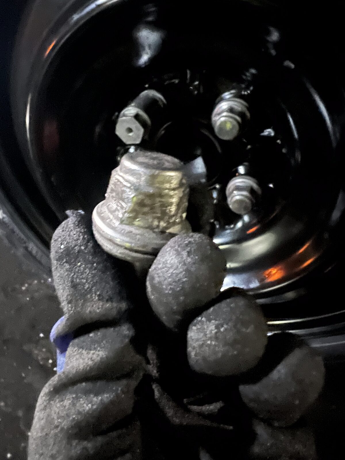 Gloved hand holding wheel lug nuts during a tire change